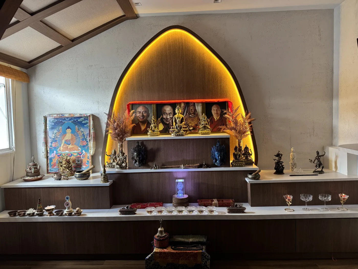 O altar de hoje, no Dojo, em um nicho iluminado com imagens, flores secas e as taças de água em fila