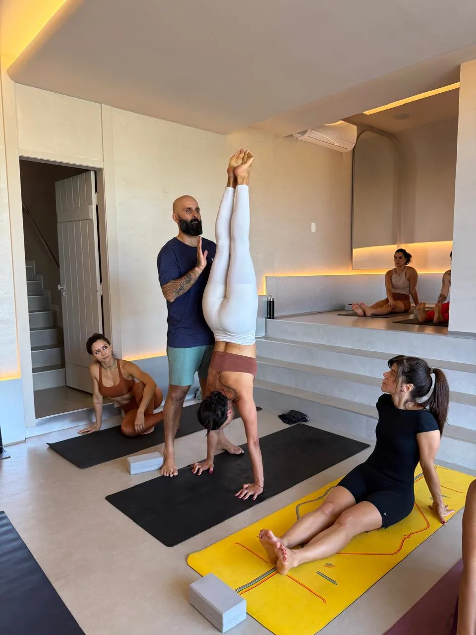 Edson apoiando uma aluna numa invertida, com a turma acompanhando de perto