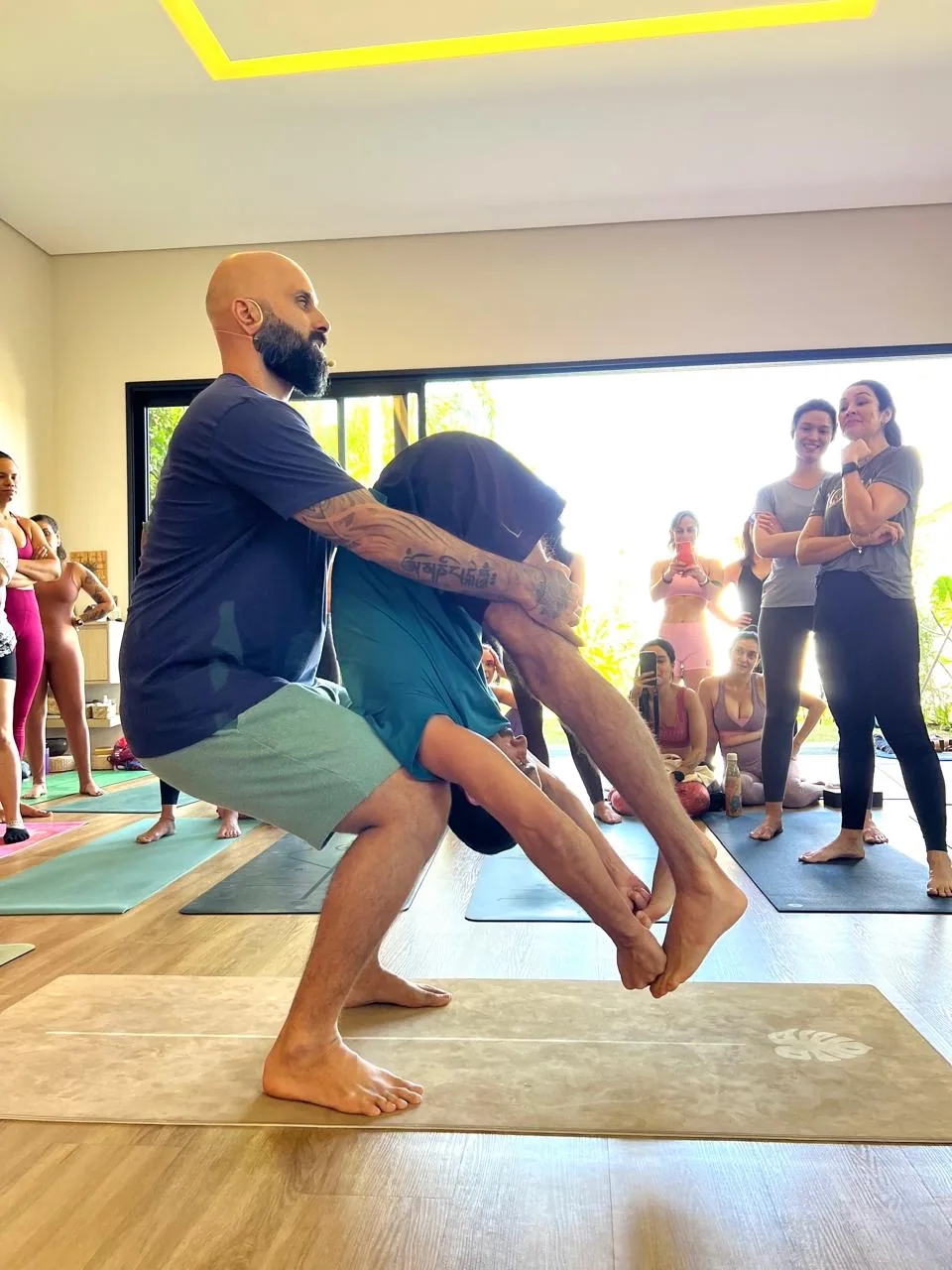 Edson Ramos sustentando uma aluna num ajuste em pé, com a turma em volta